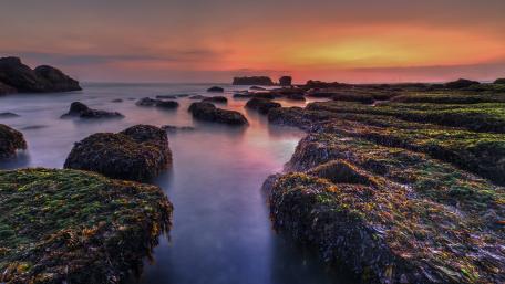 Serene Sunset Over Rocky Shoreline wallpaper