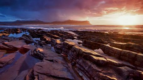 Serene Coastal Sunset Over Rocky Shoreline wallpaper