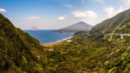 Serene Coastal Landscape with Lush Mountains wallpaper