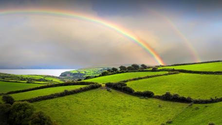 Vibrant Landscape with a Majestic Rainbow Over Green Fields wallpaper