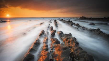 Serene Sunset Over Rocky Shoreline wallpaper