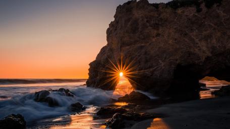 Golden Sunset Behind Rocky Archway wallpaper