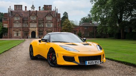 Vibrant Yellow Sports Car Against Elegant Mansion Background wallpaper