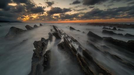 Serene Coastal Sunset Over Rocky Shoreline wallpaper