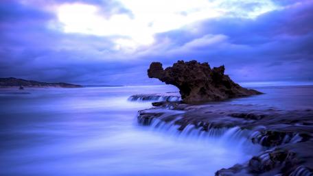 Serene Waves Embrace Rocky Shoreline wallpaper