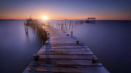 Serene Timber Pier at Sunrise Over Calm Lake wallpaper
