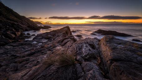 Serene Ocean Sunset Over Rocky Shoreline wallpaper