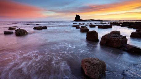Serene Sunrise Over Rocky Shoreline wallpaper