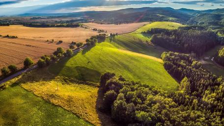 Serene Hillside Landscape Amidst Lush Fields and Forests wallpaper