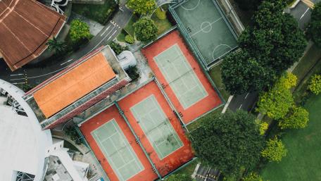 Aerial View of Tennis Courts in Vibrant Green Surroundings wallpaper