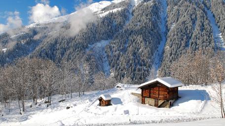 Cozy Winter Cottage Amidst Majestic Mountains wallpaper