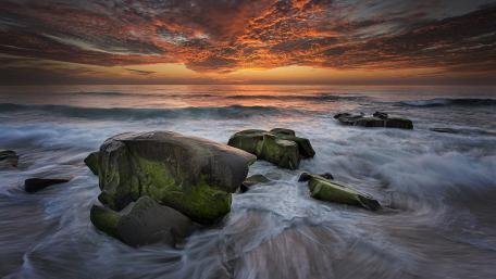 Serene Sunset Over Rocky Shoreline wallpaper