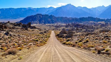 Scenic Dirt Road Through Majestic Mountains wallpaper