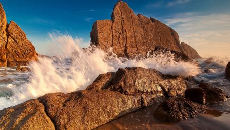 Majestic Waves Against Rugged Rocks wallpaper