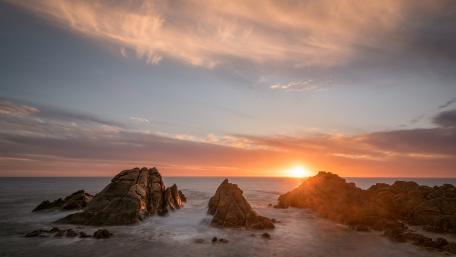 Serene Sunset Over Rocky Shoreline wallpaper