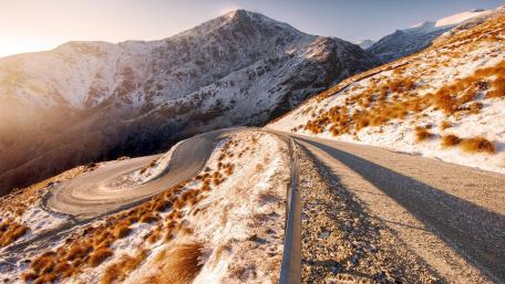 Winding Mountain Pass Surrounded by Snowy Peaks wallpaper