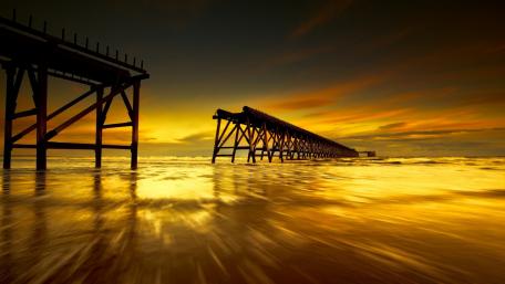 Golden Sunset Over Serene Pier Waters wallpaper