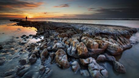 Serene Sunset Over Rocky Shoreline wallpaper