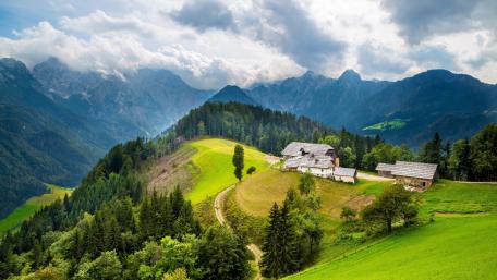 Serene Alpine Cottage Amid Majestic Mountains wallpaper
