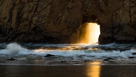 Golden Gateway Through Natural Arch at Serene Beach wallpaper