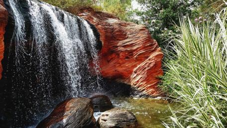 Serene Waterfall Cascading Over Vibrant Rocks wallpaper