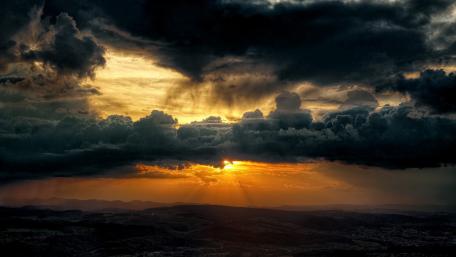 Dramatic Sunset Through Dark Clouds wallpaper
