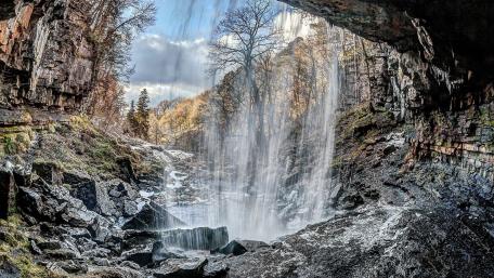 Majestic Waterfall Cascading Through a Cave Entrance wallpaper