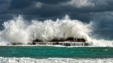 Dramatic Waves Clash Under Dark Clouds wallpaper