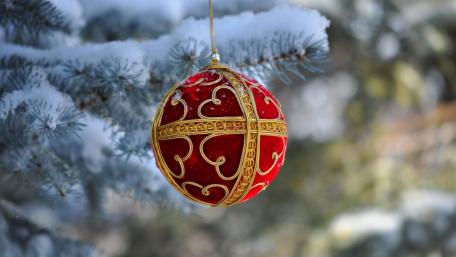 Festive Ornament Hanging from Snowy Branches wallpaper