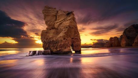 Majestic Sunset Over Shoreline Rock Formation wallpaper