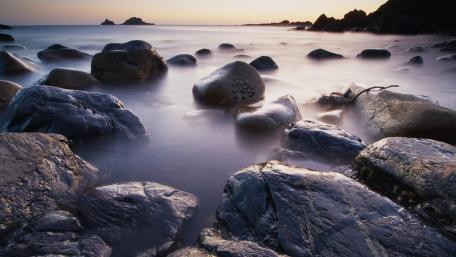 Serene Coastal Landscape with Boulders and Tranquil Waters wallpaper