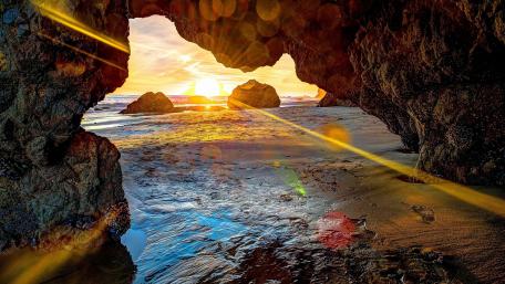 Majestic Sunset Through Coastal Cave Opening wallpaper