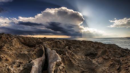 Majestic Cloudscape Over Bedrock Shoreline wallpaper