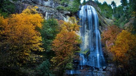 Majestic Waterfall Surrounded by Vibrant Autumn Colors wallpaper