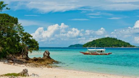 Serene Beach Escape with a Boat and Clear Waters wallpaper