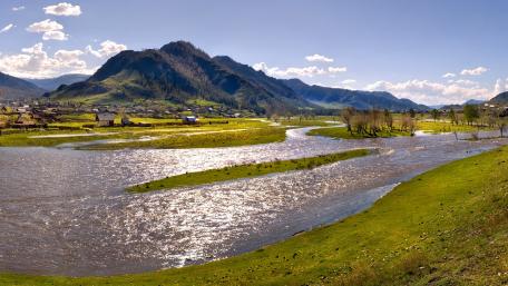 Serene Village Amidst Majestic Mountains and Rivers wallpaper