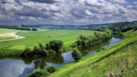 Tranquil River Flowing Through Lush Green Fields wallpaper
