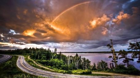 Vibrant Rainbow Over Serene Lake Roadway Scene wallpaper