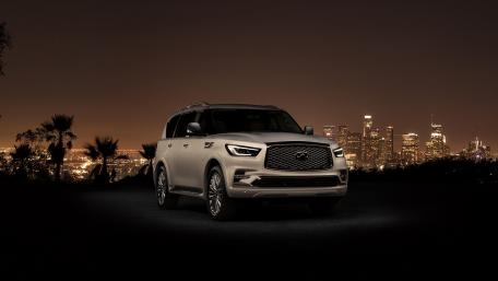Sleek Infiniti QX80 Against a Night Cityscape wallpaper