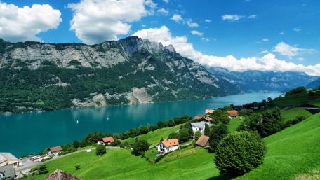 Serene Alpine River and Village Scene wallpaper