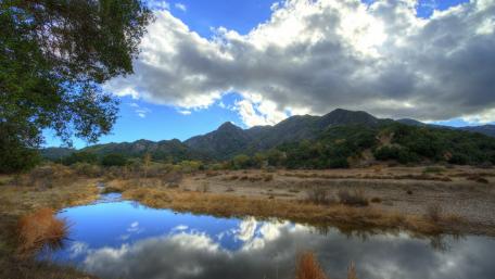 Serene River Landscape Under Cloudy Sky wallpaper