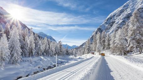 Winter Wonderland Scenic Snowy Road Through Majestic Mountains wallpaper