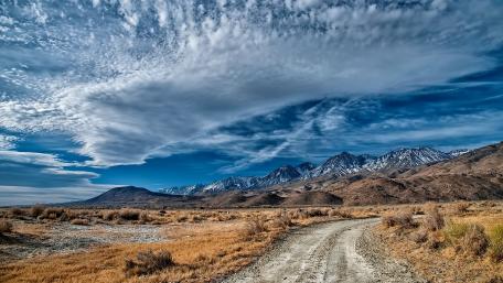 Majestic Desert Road Under Scattered Clouds wallpaper