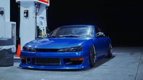 Sleek Blue Car at Night Gas Station Scene wallpaper