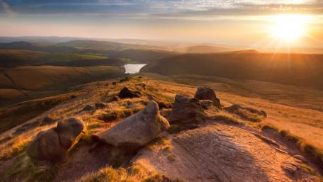 Golden Sunrise Over Rolling Hills and Calm Waters wallpaper