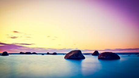 Tranquil Sunrise Over Sea Boulders wallpaper