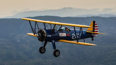 Classic Biplane in Flight Over Mountains wallpaper