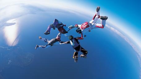 Skydivers in Freefall Over Stunning Landscape Viewpoint wallpaper