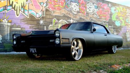 Sleek Vintage Pontiac Against a Colorful Mural wallpaper