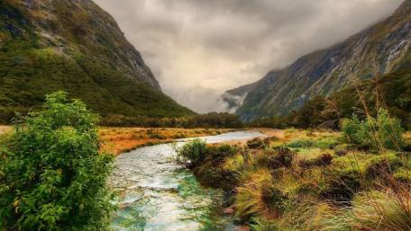 Serene Valley River Under Cloudy Skies wallpaper